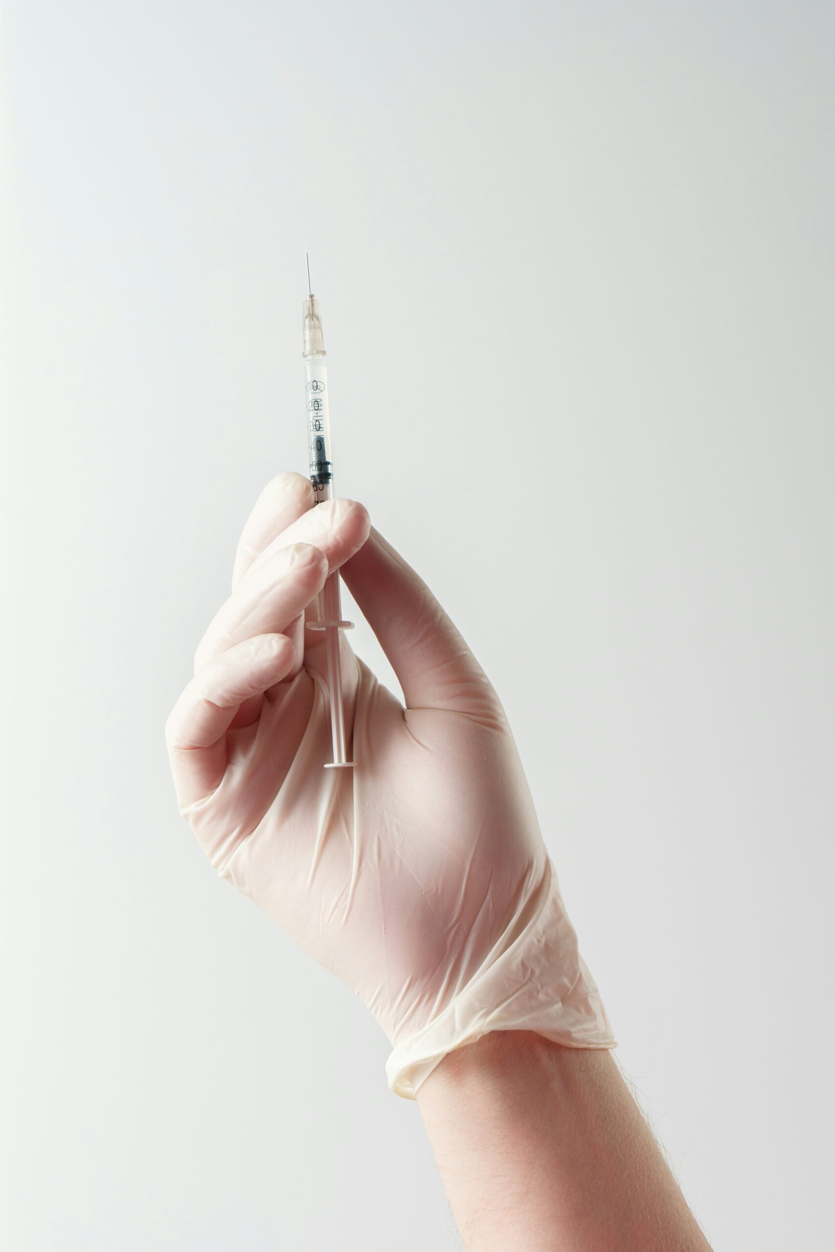 image of a gloved hand holding a syringe